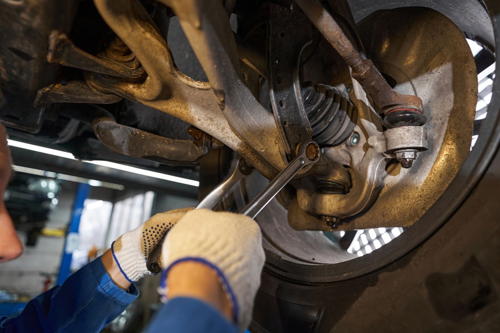 Mechanic Working On Suspension Repairs Using Wrench And Tools