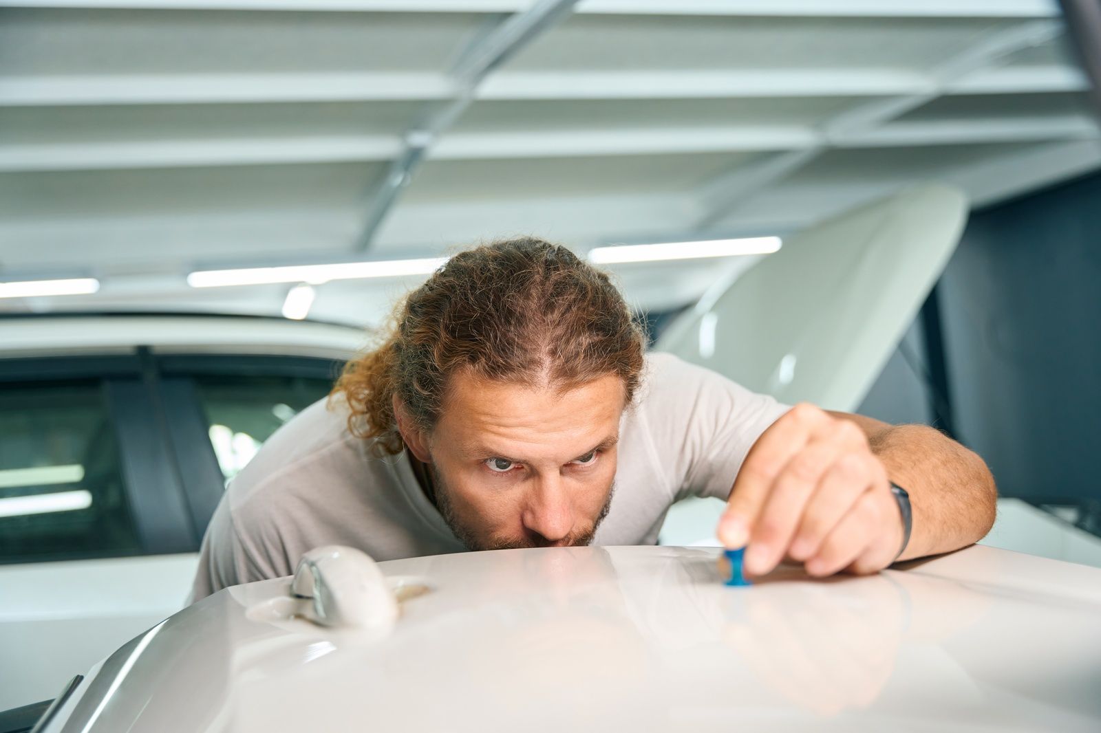 Dent Removal Service Expert Assessing Dent On Car Top Surface